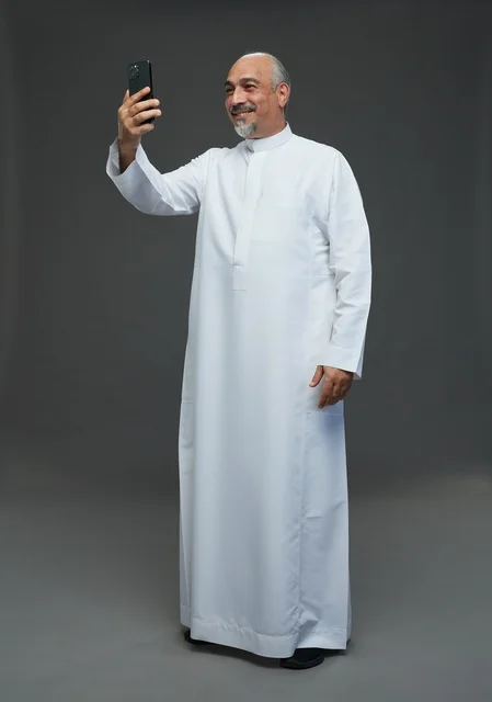 Elderly Saudi Man in Thobe Using Smartphone Studio Shot
