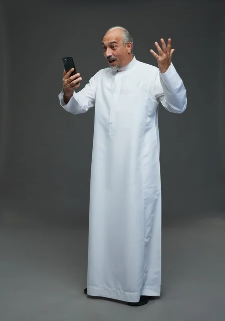 Elderly Saudi Man Using Smartphone on Grey Background