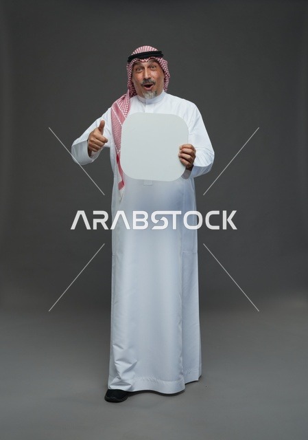 رجل سعودي مسن يحمل لوحة إعلانية بيضاء فارغة في الاستوديو