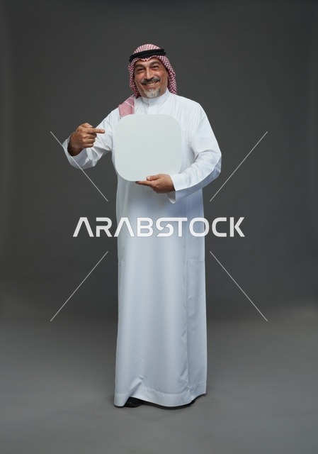 رجل سعودي مسن يحمل لوحة إعلانية فارغة بخلفية رمادية