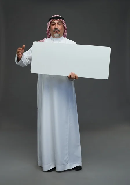 رجل سعودي مسن يحمل لوحة إعلانية بيضاء فارغة