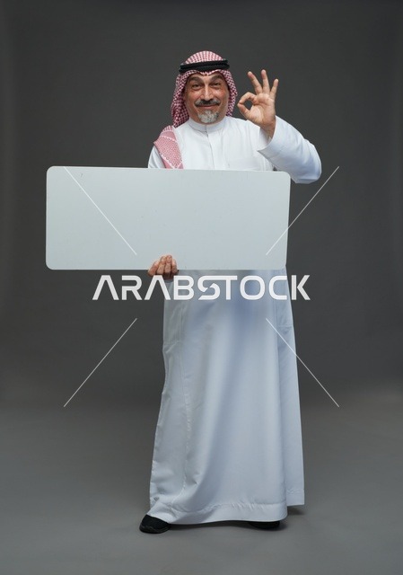 رجل سعودي مسن يحمل لوحة إعلانية بيضاء فارغة
