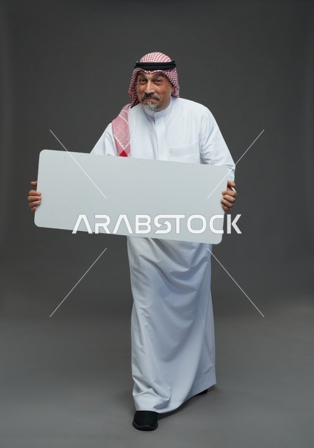 رجل سعودي مسن يحمل لوحة إعلانية فارغة في الاستوديو