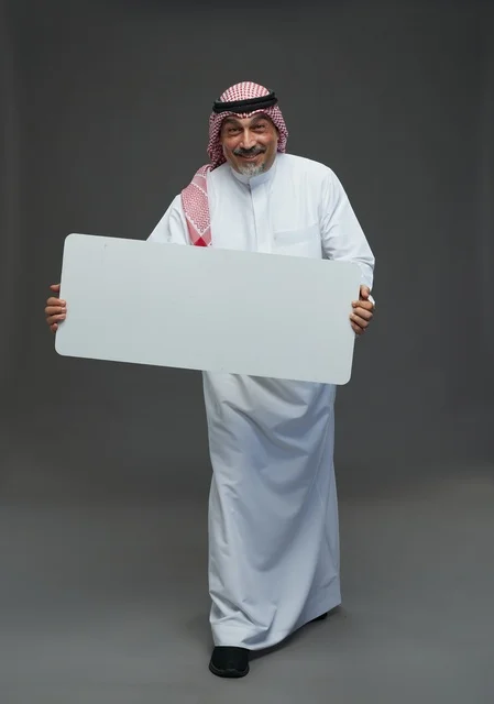 رجل سعودي مسن يحمل لوحة إعلانية بيضاء فارغة
