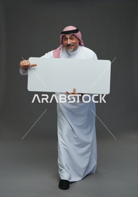 رجل سعودي مسن يرتدي الزي التقليدي يحمل لوحة إعلانية بيضاء