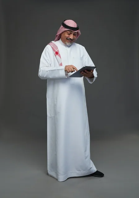Senior Saudi Man Using Tablet on Grey Background