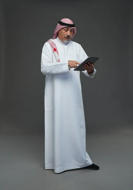 Elderly Saudi Man Using Digital Tablet on Grey Background