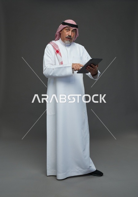 رجل سعودي مسن يستخدم جهاز لوحي في الاستوديو