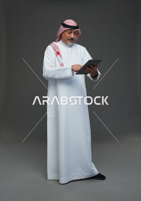 رجل سعودي مسن يستخدم جهاز لوحي في الاستوديو