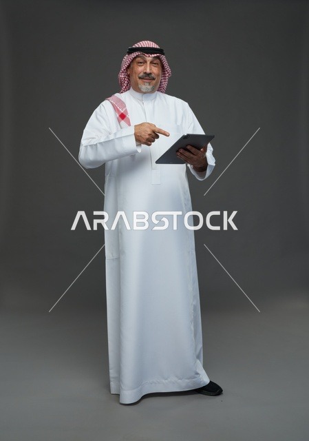 Elderly Saudi Man Using Digital Tablet in Grey Studio