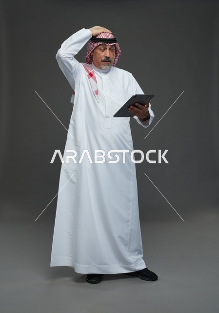Elderly Saudi Man Using Tablet with Worried Expression