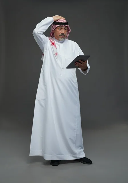 Elderly Saudi Man Using Tablet with Worried Expression