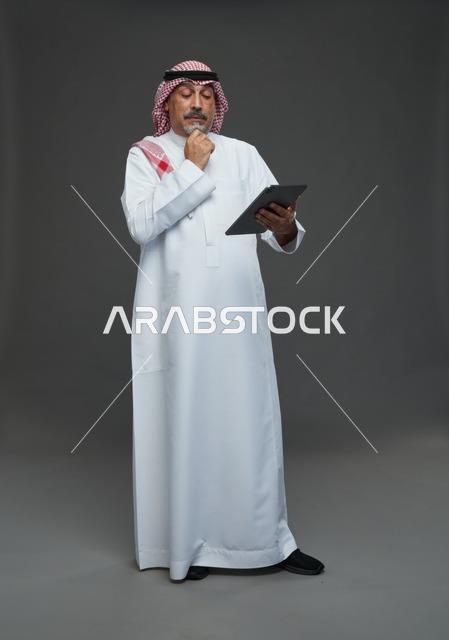 رجل سعودي مسن يستخدم جهاز لوحي في الاستوديو