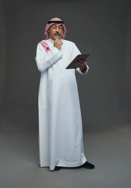 Elderly Saudi Man Using Tablet on Grey Background