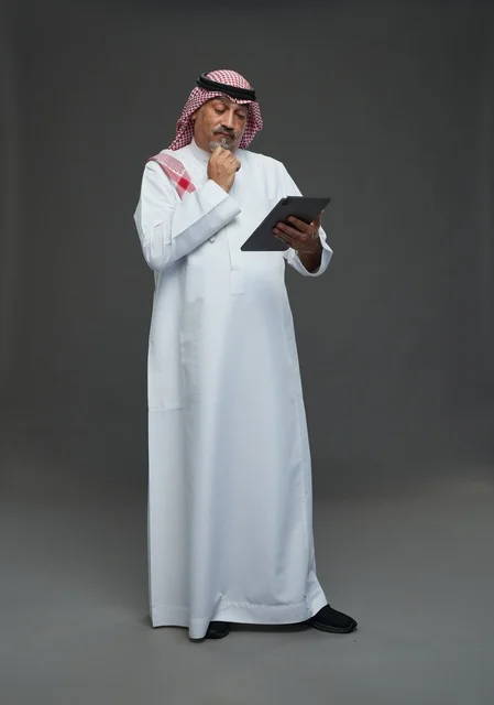 Saudi Elderly Man Using Tablet in Traditional Thobe