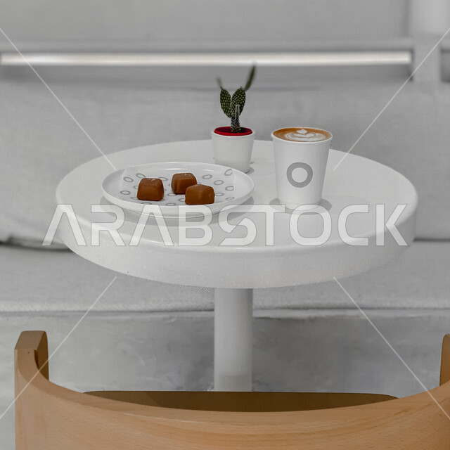 صورة لكوب القهوة على طاولة في احد الكافيهات، قهوة اسبريسو، طبق يحتوي على قطع شوكولاتة، مشروبات ساخنة، جلسات هادئة في مقاهي السعودية