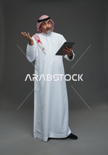 رجل سعودي مسن مع جهاز لوحي في الاستوديو