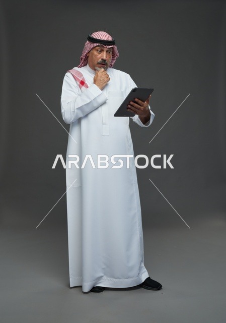 Elderly Saudi Man Using Digital Tablet on Grey Background