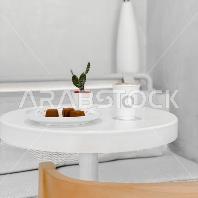 صورة لكوب القهوة على طاولة في احد الكافيهات، قهوة اسبريسو، طبق يحتوي على قطع شوكولاتة، مشروبات ساخنة، جلسات هادئة في مقاهي السعودية