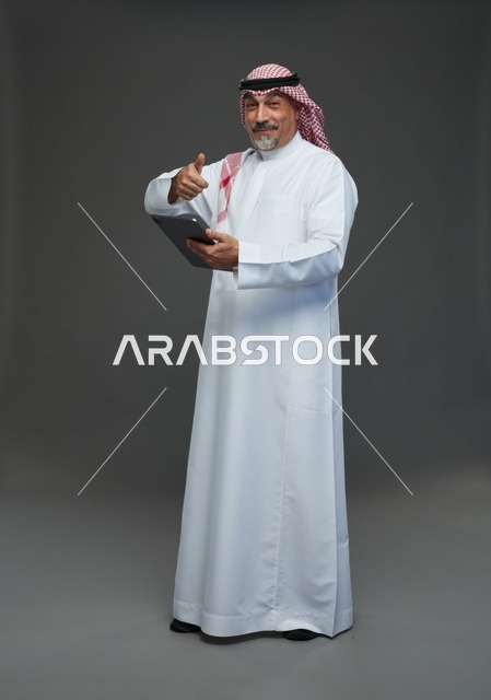 رجل سعودي مسن يستخدم الجهاز اللوحي مع علامة إعجاب