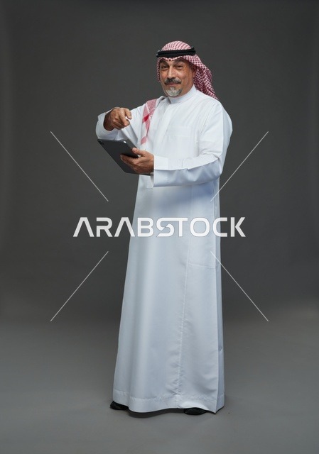 رجل سعودي مسن مع جهاز لوحي خلفية رمادية