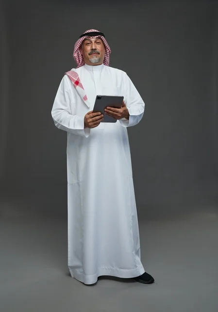 رجل سعودي مسن يحمل جهاز لوحي في الاستوديو