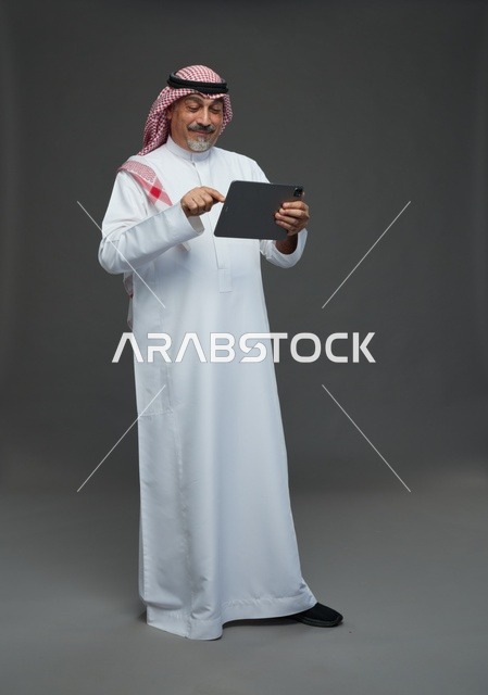 Saudi Elderly Man Using Digital Tablet on Grey Background