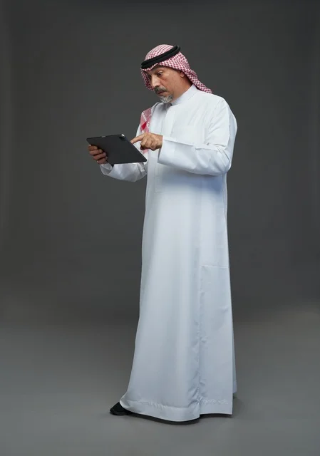 Senior Saudi Man Using Digital Tablet on Grey Background