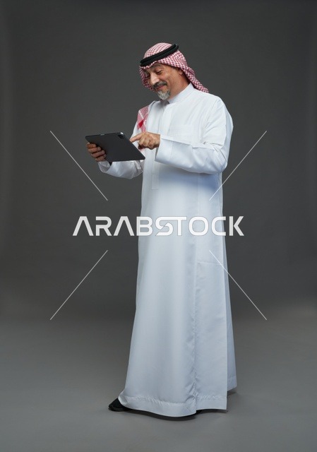 رجل سعودي مسن يستخدم جهاز لوحي في الاستوديو