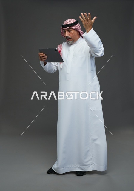 Elderly Saudi Man Using Tablet on Grey Background
