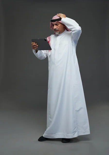 Elderly Saudi Man Using Tablet with Confused Expression