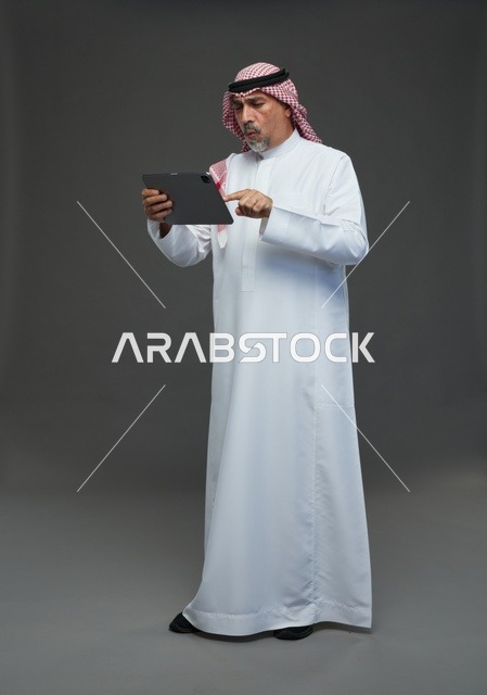 Senior Saudi Man Using Tablet against Grey Background