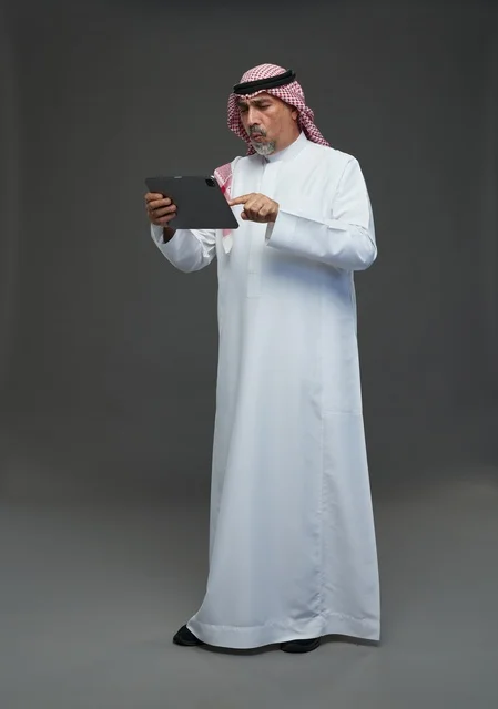 Senior Saudi Man Using Tablet against Grey Background