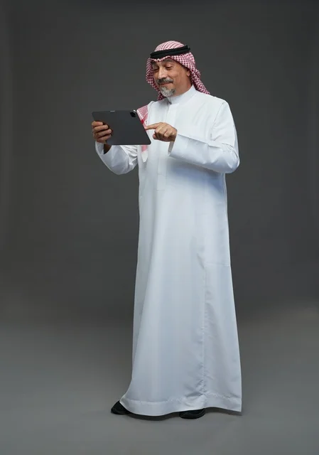 Senior Saudi Man Using Digital Tablet on Grey Background