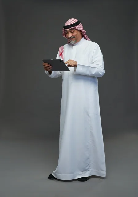 رجل سعودي مسن يستخدم جهاز لوحي في الاستوديو