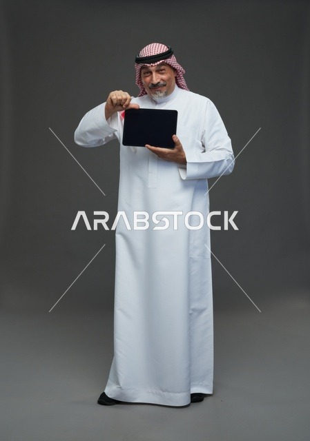 Elderly Saudi Man with Tablet on Grey Studio Background