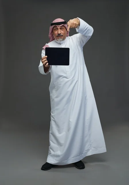 رجل سعودي بالثوب التقليدي يستخدم جهاز لوحي