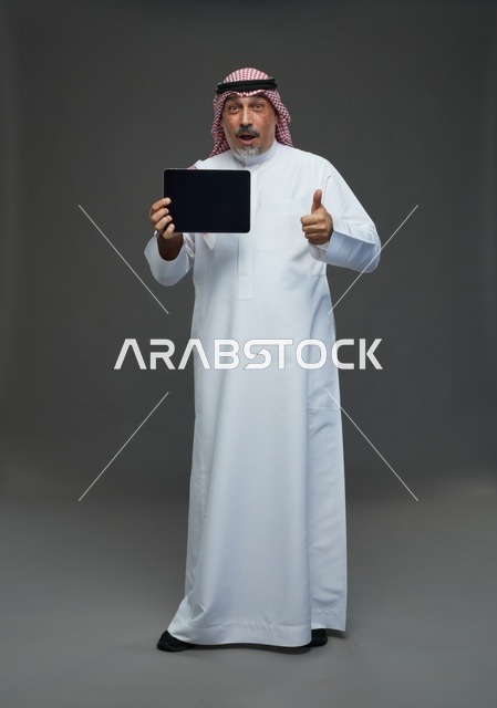 رجل سعودي مسن مع جهاز لوحي وتعبير مندهش