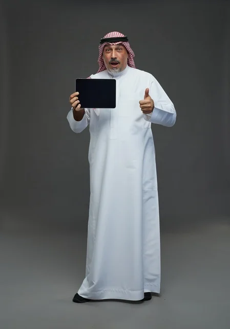 رجل سعودي مسن مع جهاز لوحي وتعبير مندهش