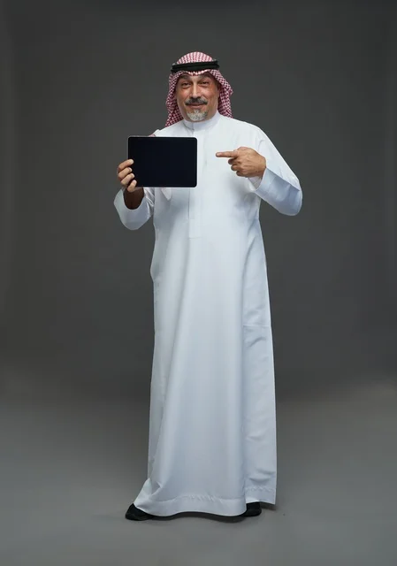 Saudi Senior Man Holding Digital Tablet Against Grey Background