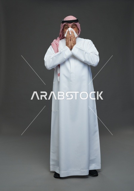 رجل سعودي مسن يعطس في منديل داخل الاستوديو