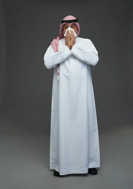 Elderly Saudi Man Sneezing into Tissue in Studio