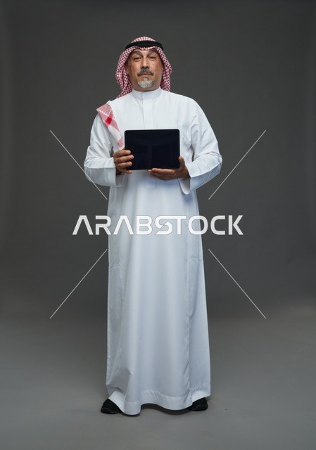 Saudi Elderly Man Holding Digital Tablet on Grey Background