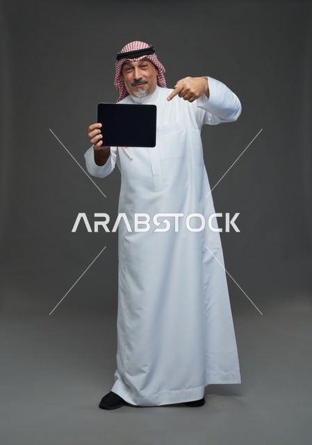 رجل سعودي مسن يشير إلى شاشة جهاز لوحي