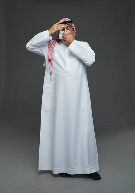 Elderly Saudi Man Sneezing into Tissue in Studio