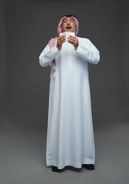 رجل سعودي مسن يعطس في منديل ورقي في استوديو تصوير