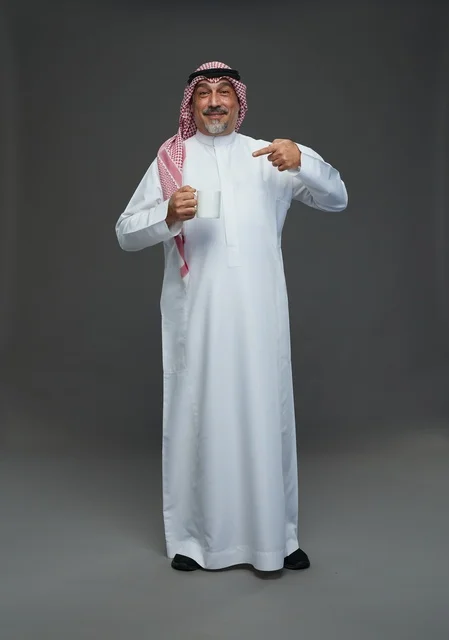 Senior Saudi Man Pointing at White Coffee Mug in Studio