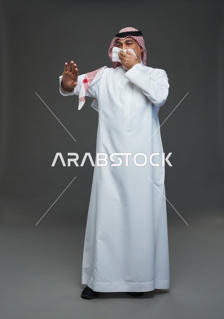 رجل سعودي مسن يعطس في منديل في الاستوديو