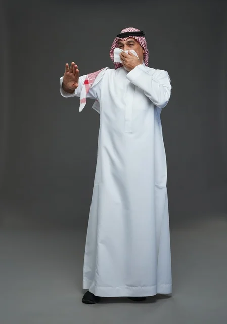 Elderly Saudi Man Sneezing into Tissue in Studio