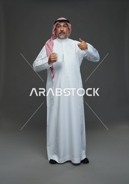 رجل سعودي يحمل كوب قهوة ويشير بالإعجاب